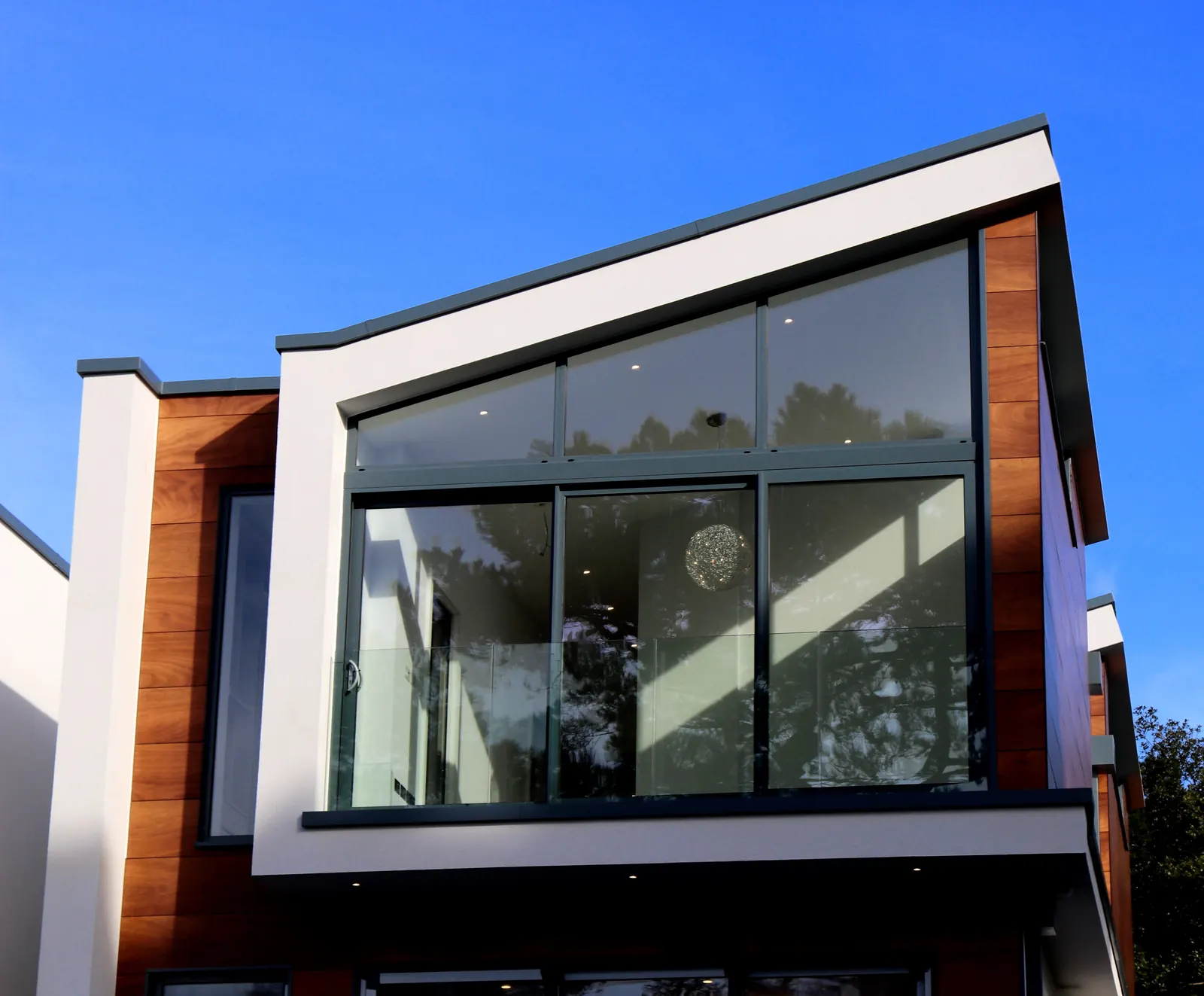A timber and glass house against a deep blue sky