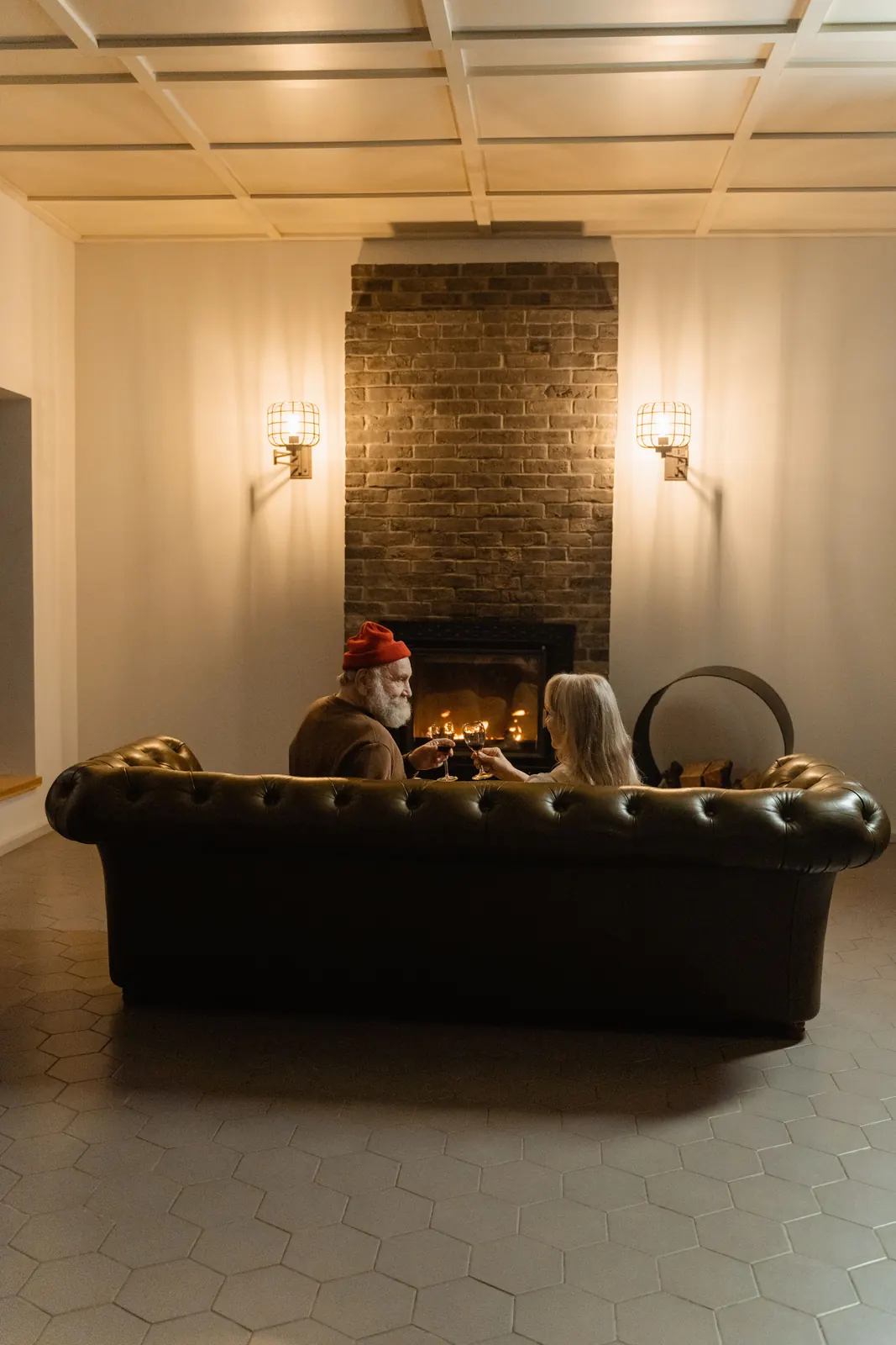A couple talking by an open fire on a leather sofa