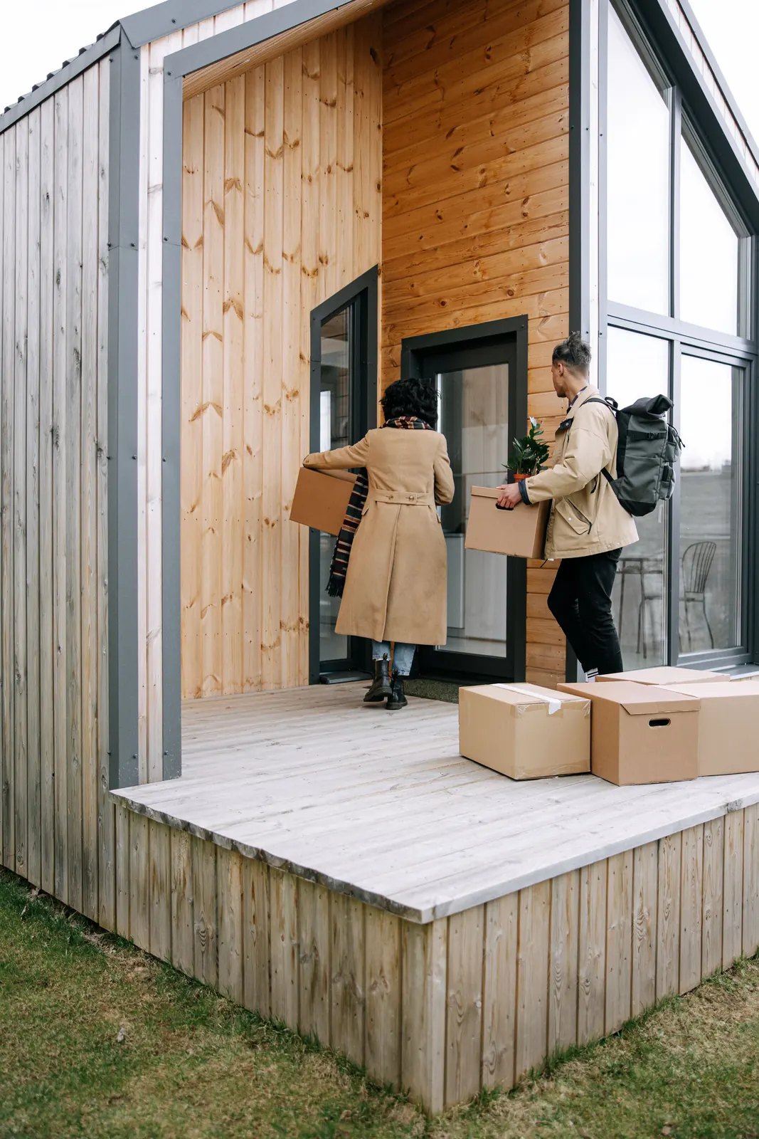 A couple carrying boxes into a timber A-frame house