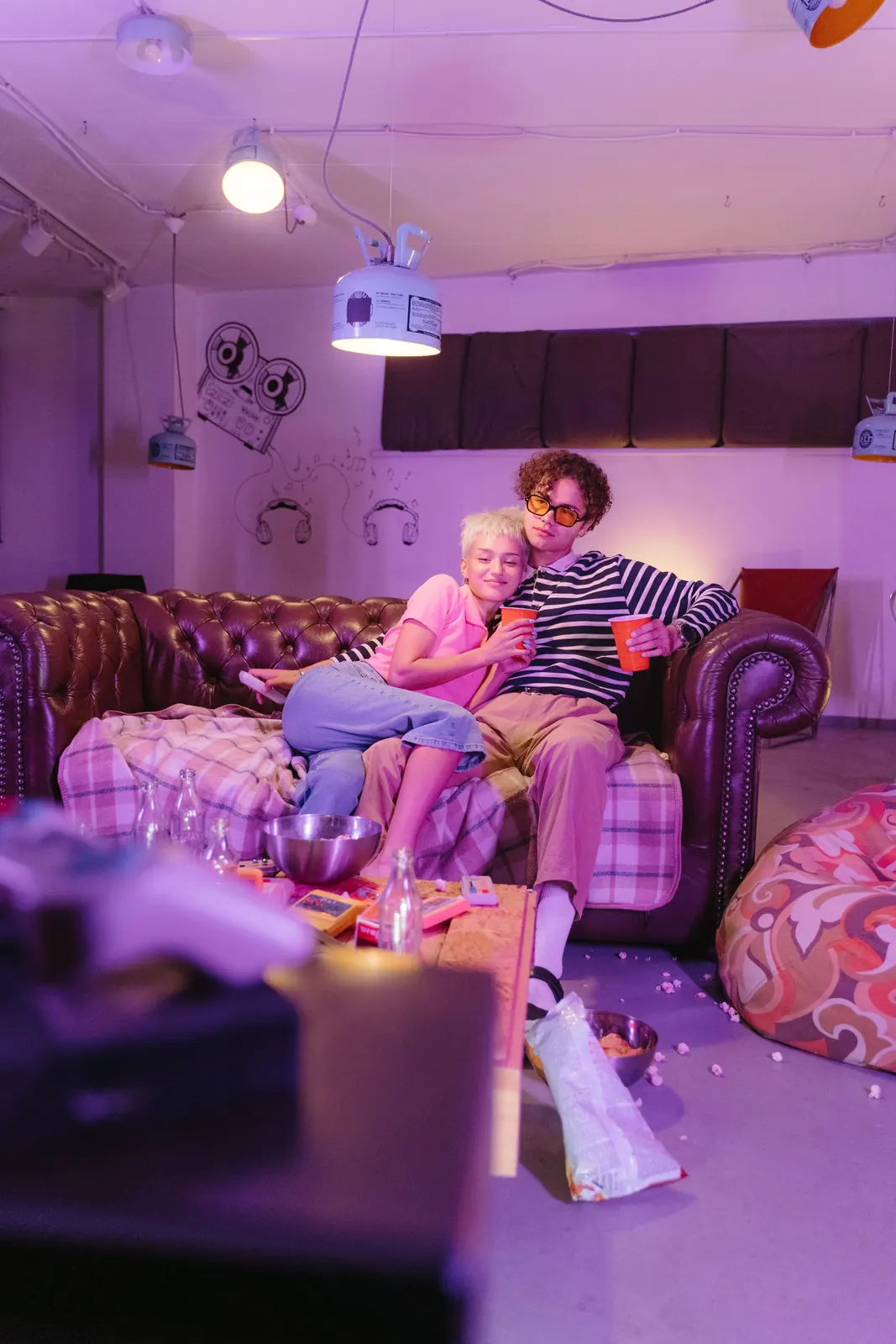 Two friends laughing on a chesterfield under pink light